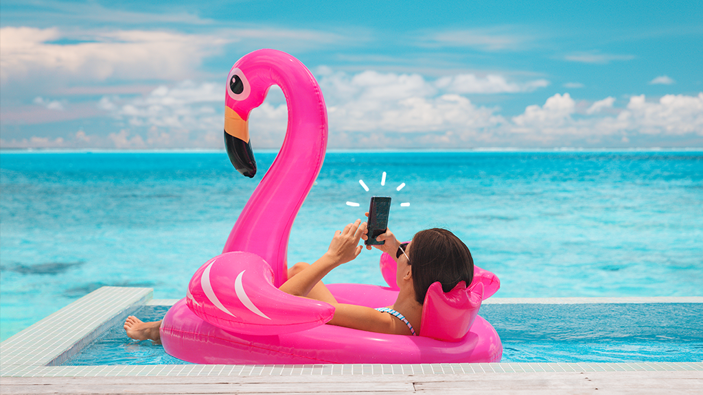 Woman in pool on flamingo float using her phone 