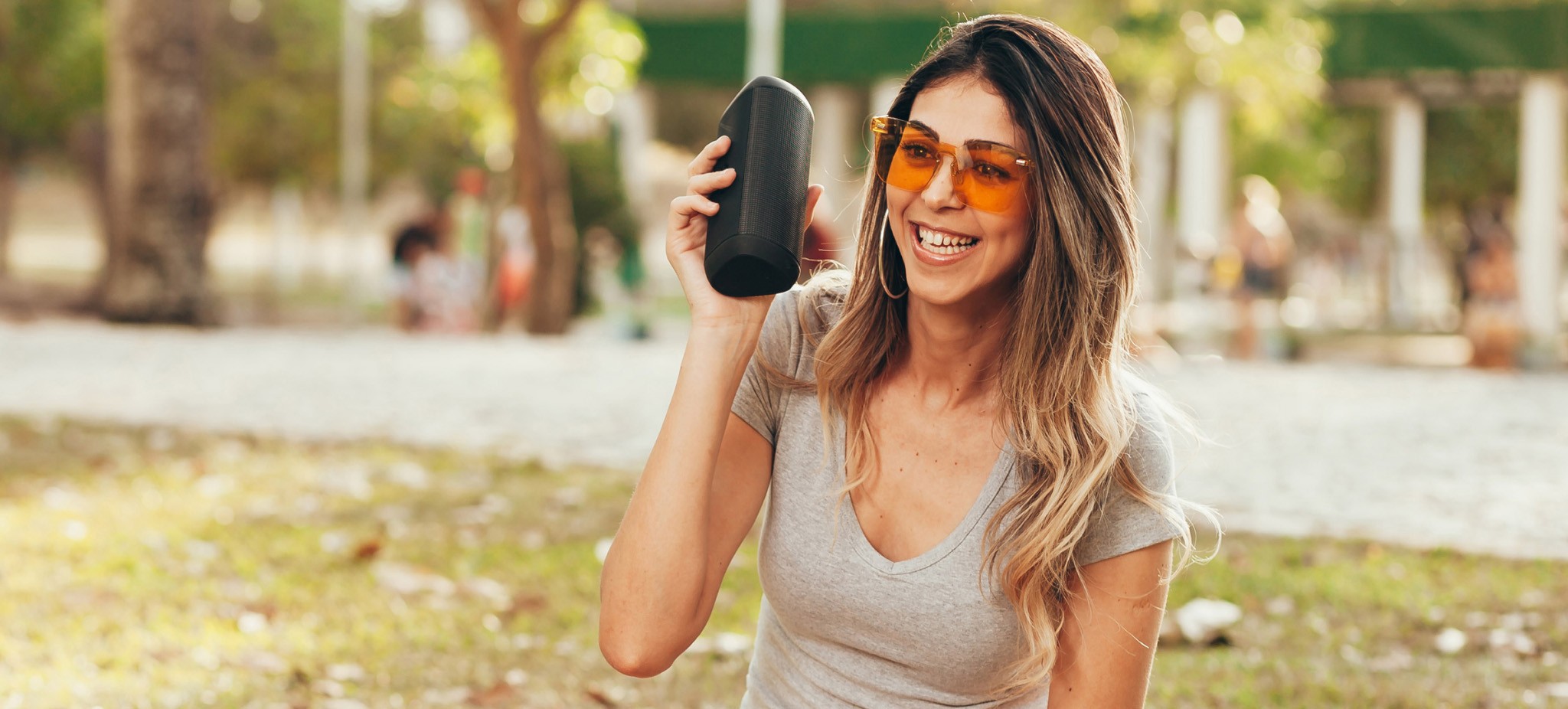 woman holding a bluetooth speaker at park