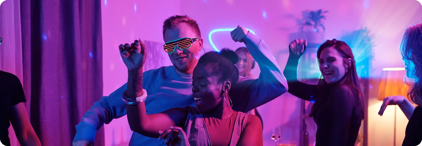 People dancing under colorful smart LED lights at a party.