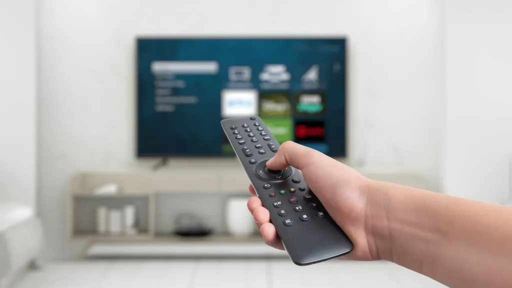 Lifestyle image of hand holding a remote pointing at a TV