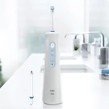 Canule Oral-B AquaCare Série 4 à côté du manche de la brosse sur le lavabo de la salle de bains. 