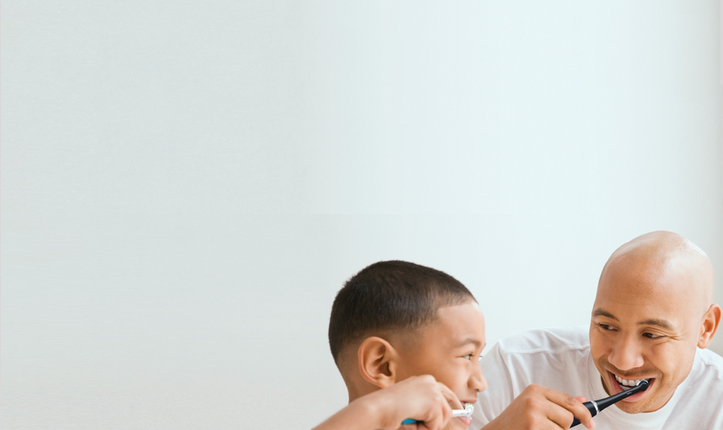 Un homme et un enfant se brossant les dents avec les brosses à dents Oral-B