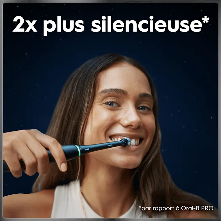 Brosse à dents électrique en utilisation, avec texte "2x plus silencieuse* *par rapport à Oral-B PRO" sur fond bleu nuit.