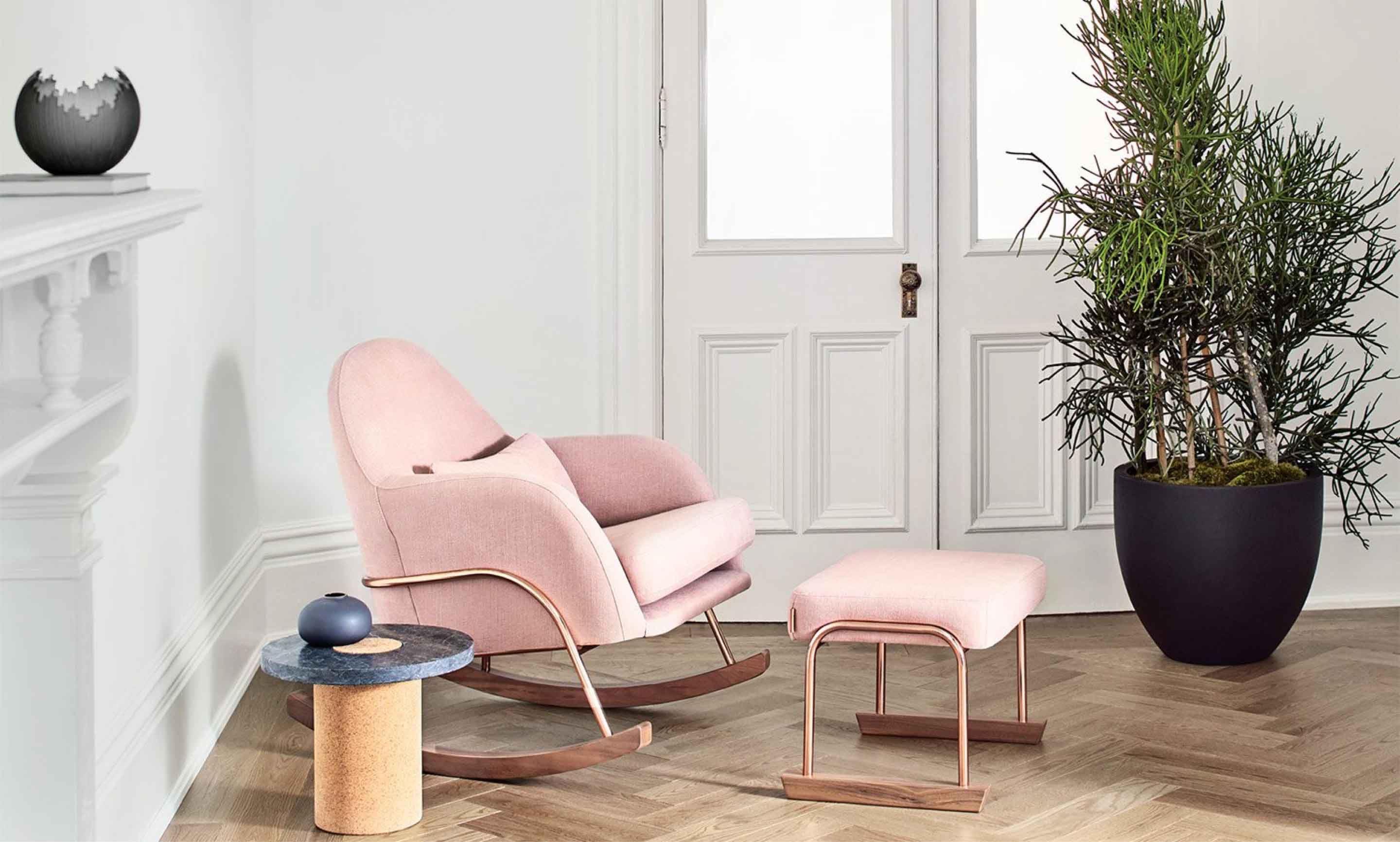 A modern and stylish pink fabric rocker and matching footrest is set in the corner of a room.