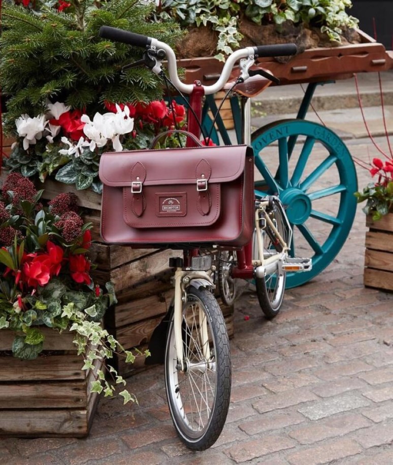 A burgundy satchel is affixed to the front of a bike.