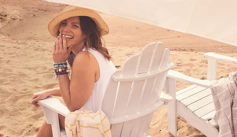A smiling woman sitting on a chair at the beach