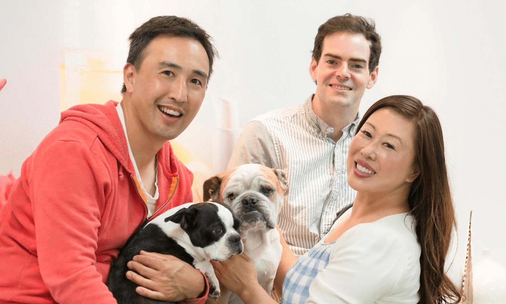 100% Pure's founders, James Wang, Susie Wang, and Ric Kostick pose with two small dogs.