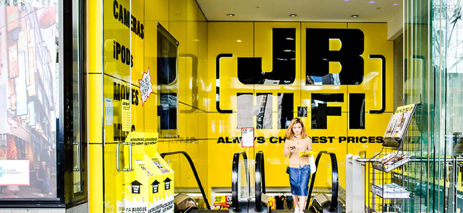 Woman exiting JB Hi-Fi store.