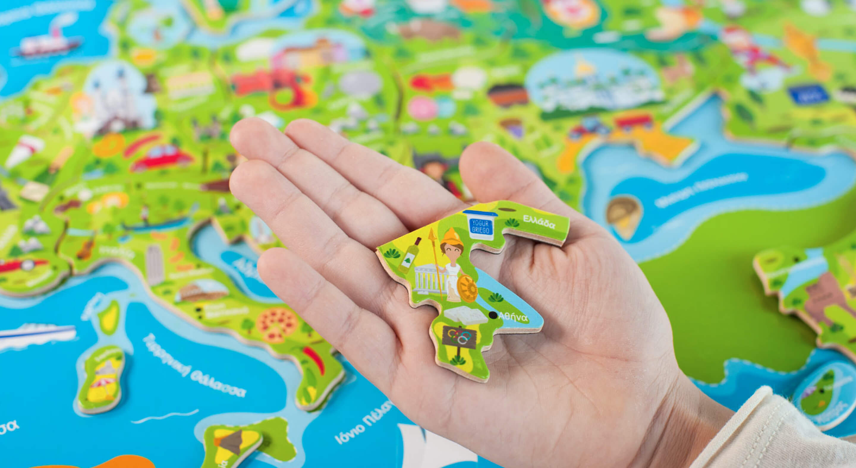 A brightly colored puzzle piece in someone's hand with a puzzle of Europe in the background