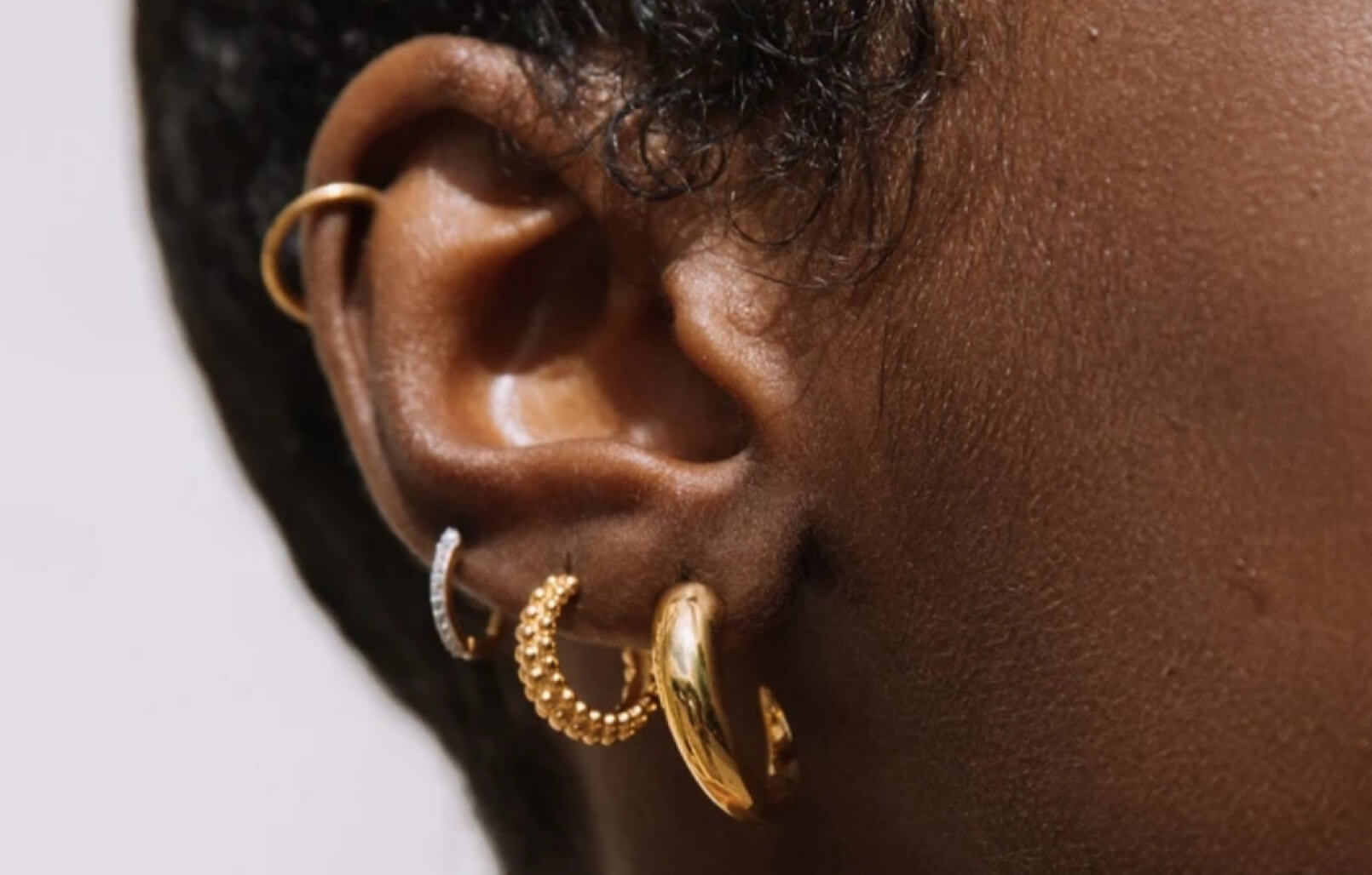 A woman's ear with four piercings, wearing four Missoma hoops.