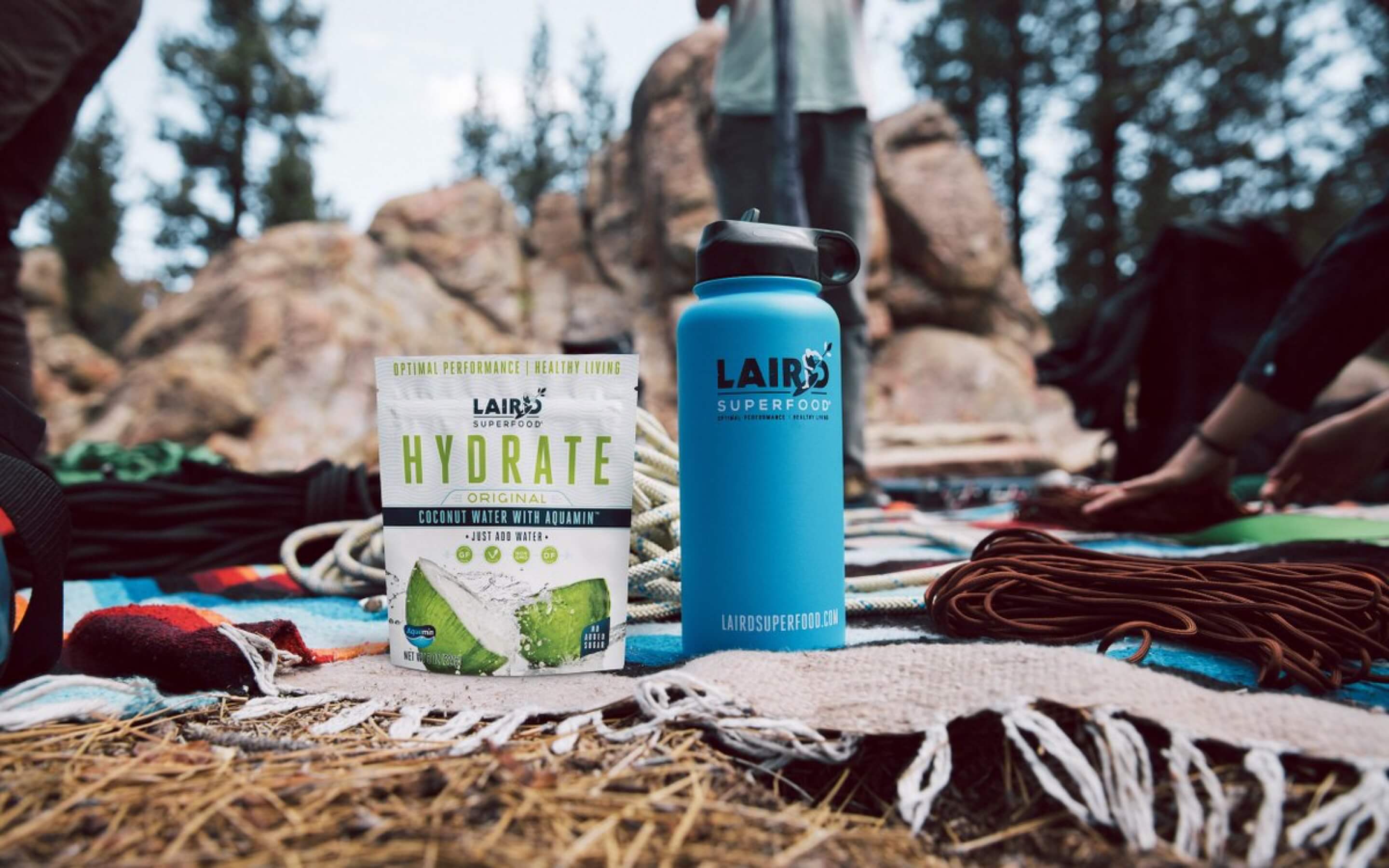 A Laird Superfood package sits beside a blue Laird Superfood water bottle in an outdoor setting.