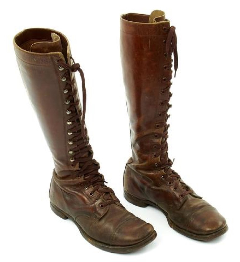 A pair of brown, calf-high leather military boots are shown against a white background.