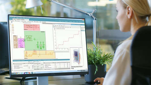 Engineer sitting at a desk working on a computer monitor to design an ambulatory infusion pump using system simulation software. 
