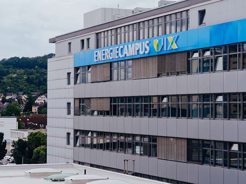 Кученце златен ретривър седи на трева, гледа нагоре с ярки очи и любопитен израз.