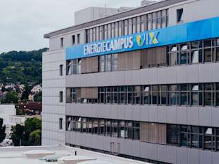 A golden retriever puppy sits on grass, looking up with bright eyes and a curious expression.