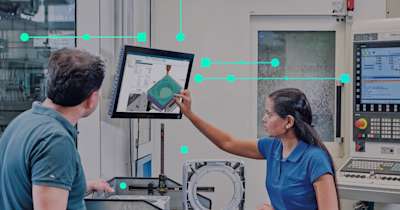 A man and woman in a shopfloor setting reviewing a part using NX CAM software. 
