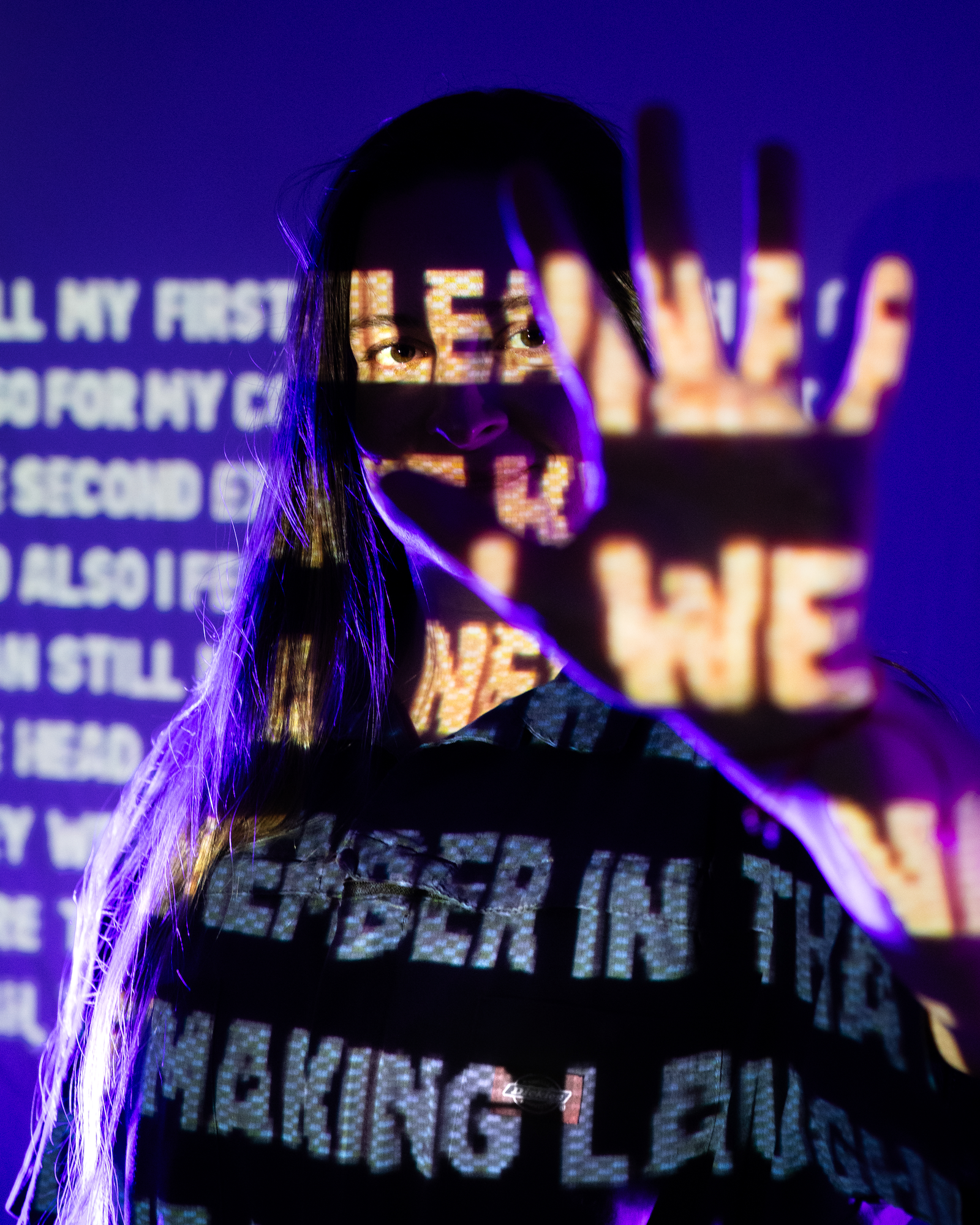 A person standing in darkness with letters projected onto their outstretched hand