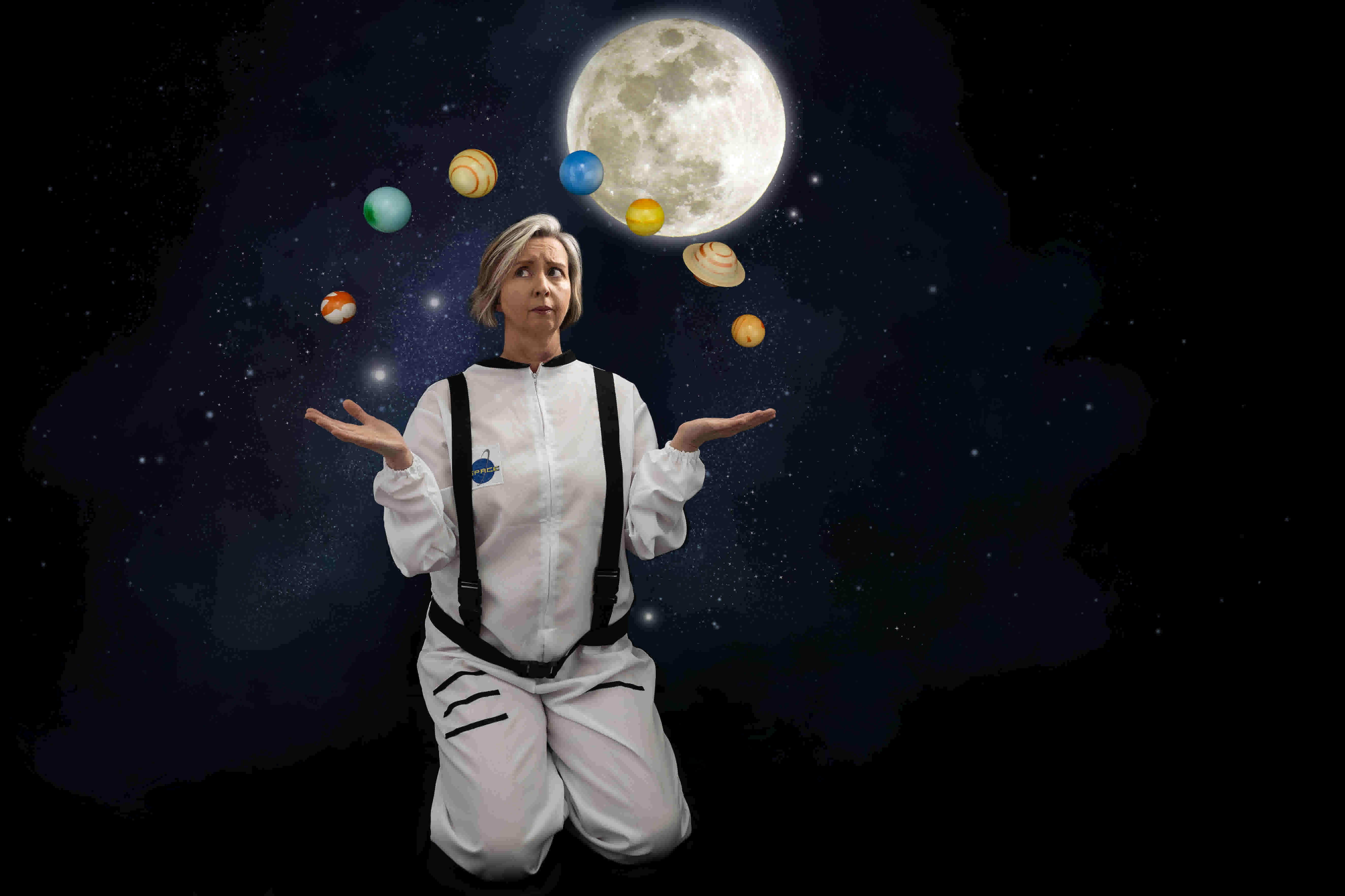 A woman kneels while planets float around her head