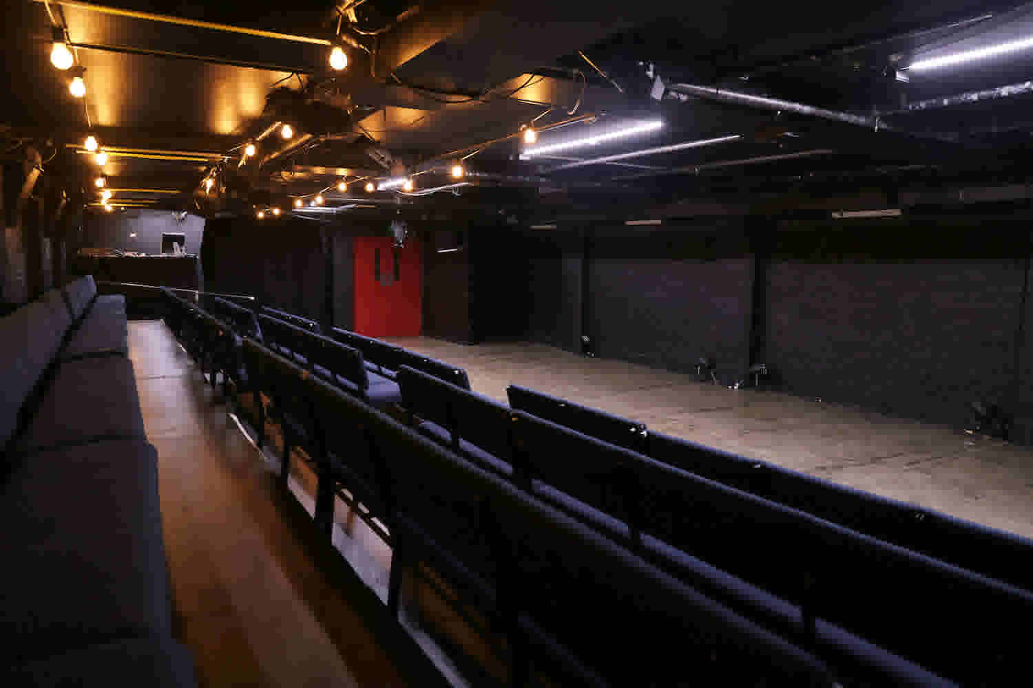 Basement Theatre's main Theatre space showing the seating block, stage, operating desk and entrance - taken from the back of the seating block. 