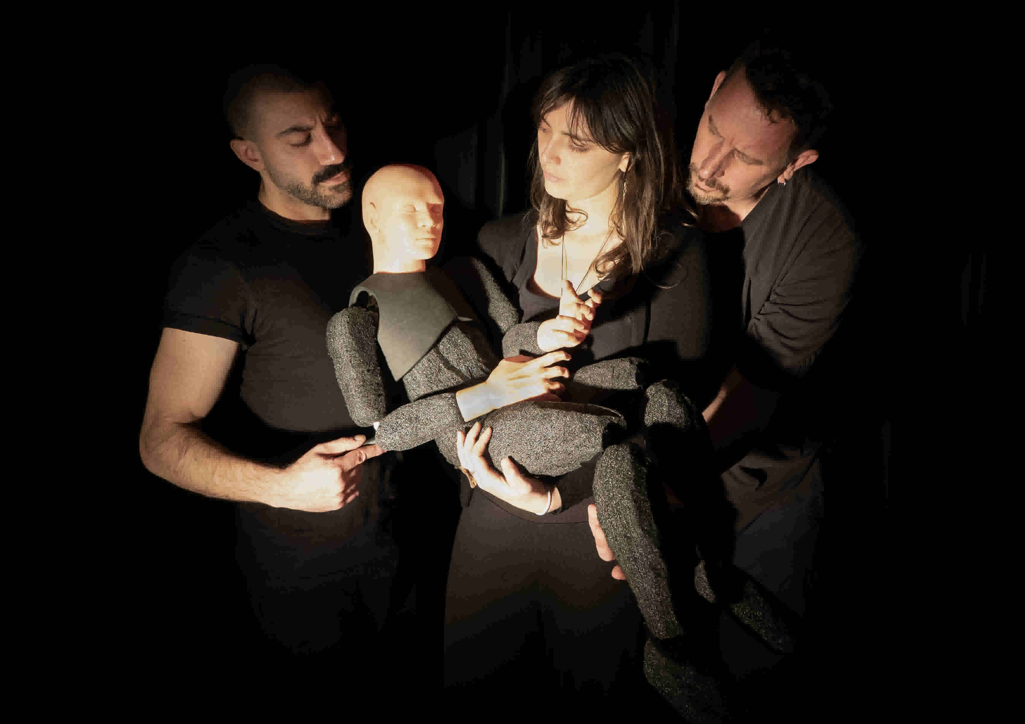 Three people hold a puppet that looks like a prisoner. They are looking on sympathetically.