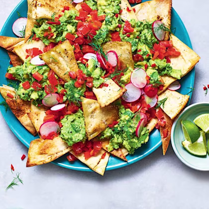 Homemade tortilla chips with crushed avocado and tomato salsa