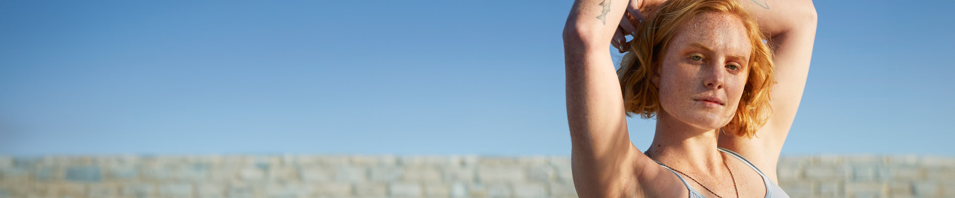 Girl holding hands up showing armpits outside in sunlight