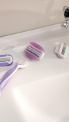 Purple colored refillable Gillette Venus razor with a detached razor head and two other razor heads next to it