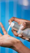 Woman squeezing product from a squeeze cap of a Venus cleanser + shaving gel container