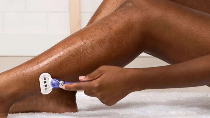 Woman Shaving Her Legs in a Bathroom