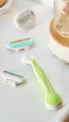 Green-colored refillable Gillette Venus razor with a detached razor head and two other razor heads next to it