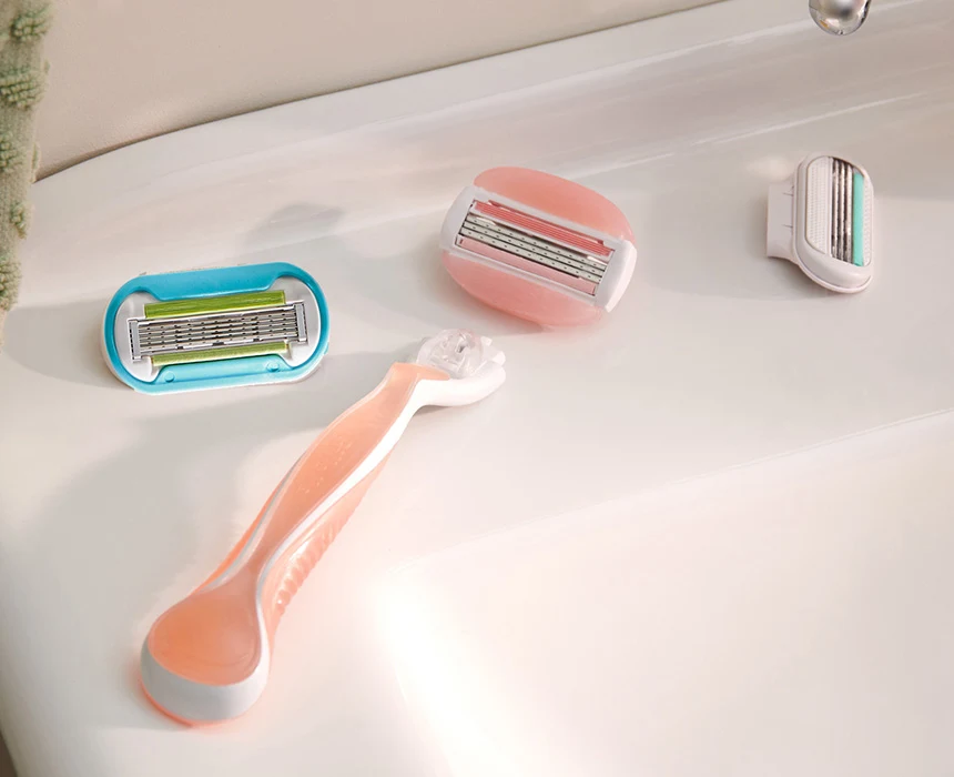 Orange razor with a detached razor head and two other razor heads next to it on a bathroom sink