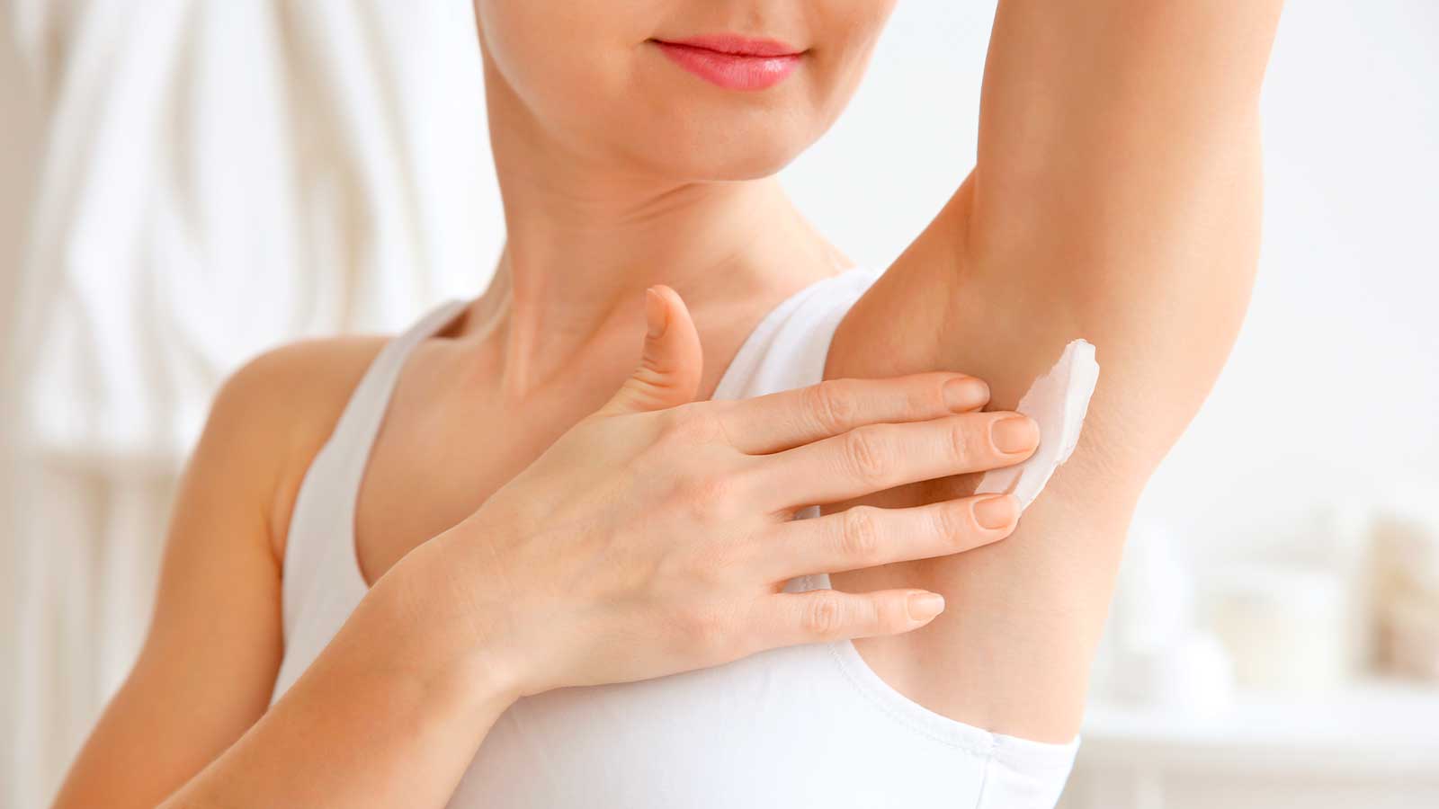 Woman applying cream to her armpit