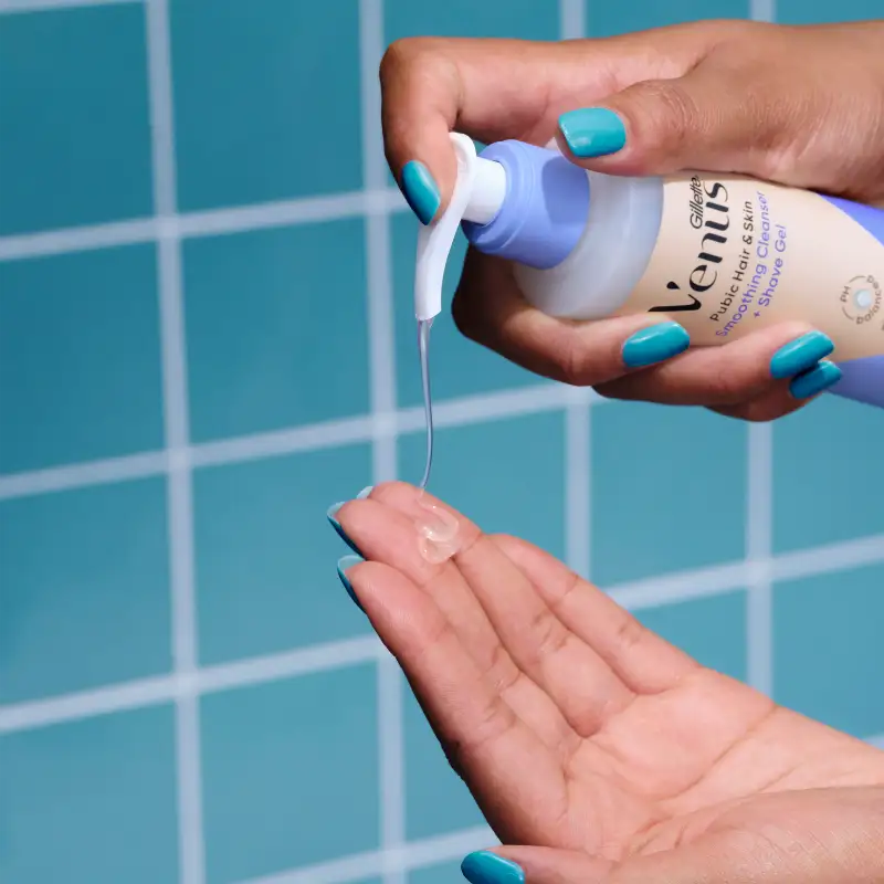 Venus 2-in-1 cleanser and shaving gel with a razor, placed on a surface with water and blue tiled background.