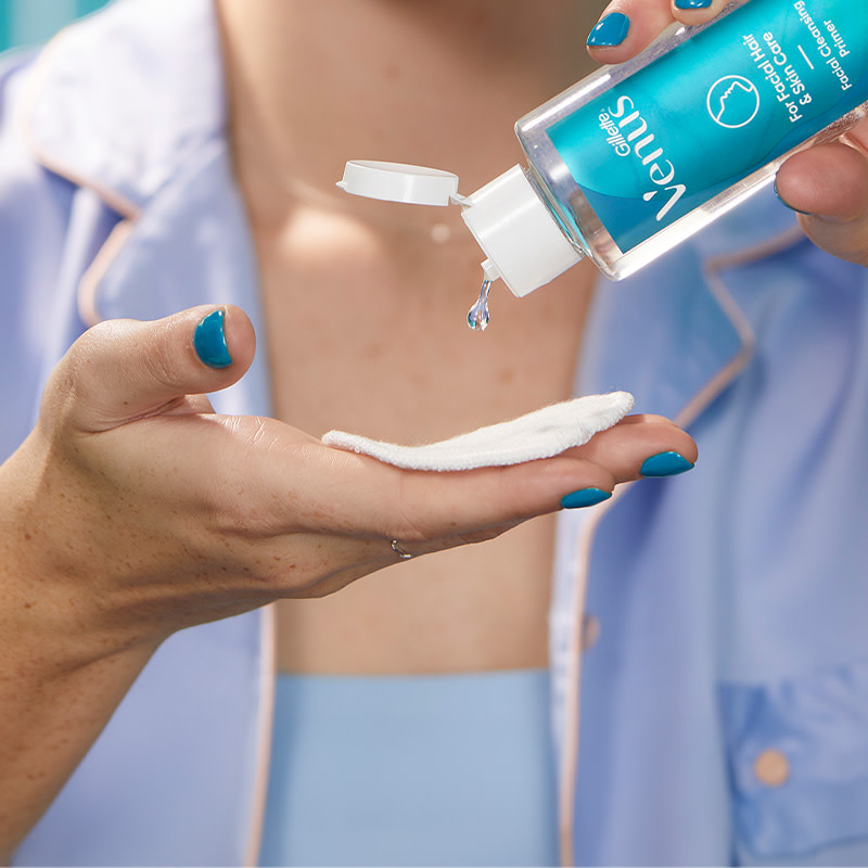 Woman pouring Facial Hair & Skin Primer onto a cotton pad which she holds in her hand