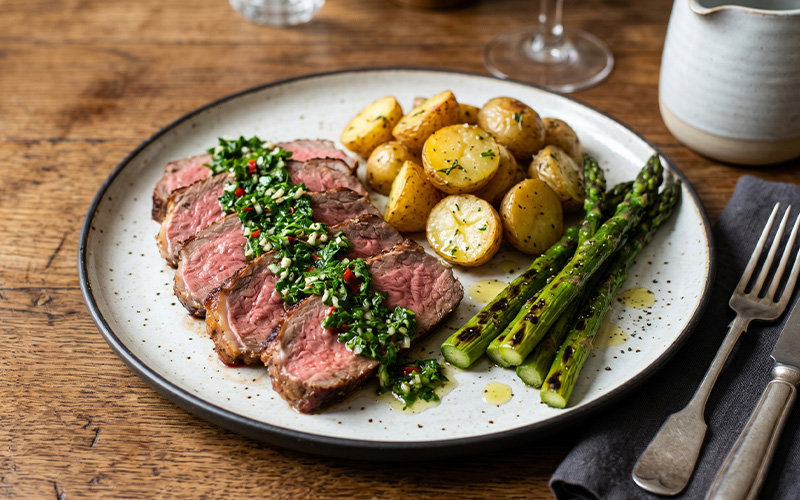 Slices of roast sirloin beef topped with green chimichurri sauce, served with Jersey Royal potatoes and charred asparagus.