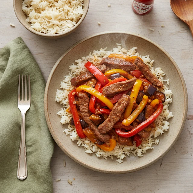 sliced steak and peppers on a bed of rice