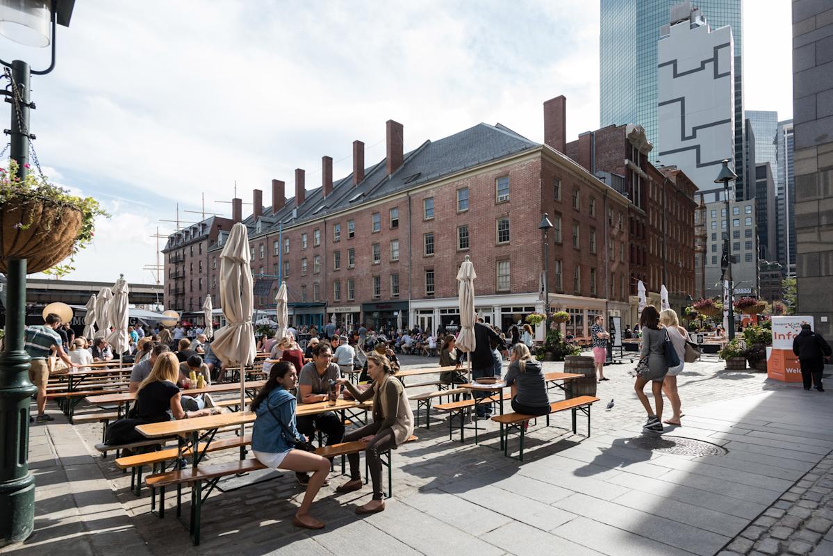 People seating at outdoor benches in Seaport, NYC