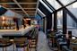 Modern rooftop bar with panoramic city views, featuring a long counter lined with leather stools. 