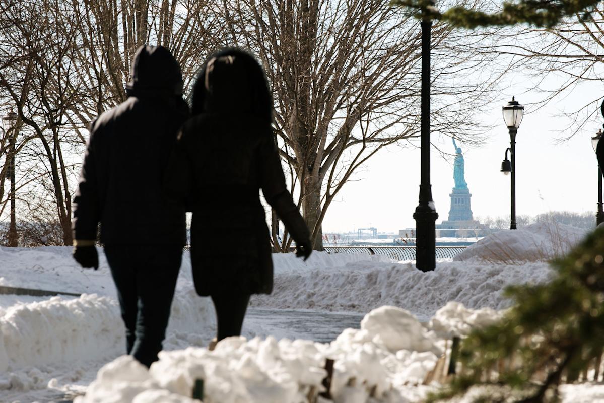 walking through battery park with view of statue of libertuy 