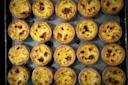 Rows of golden-brown egg tarts neatly arranged on a baking tray, each with a slightly browned top and flaky pastry crust, creating a visually appealing pattern.