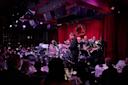 a band playing in a dark room with red curtains.