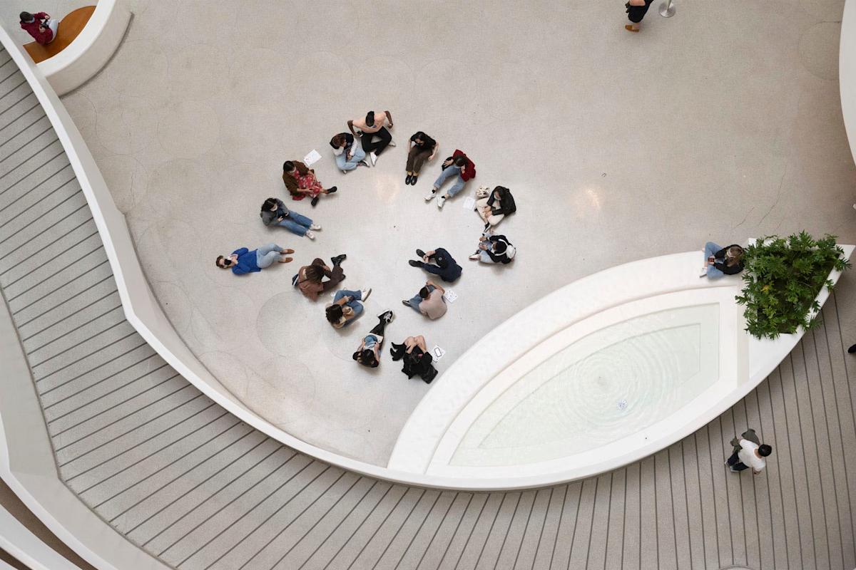 Group of teens sitting on the floor sketching in Guggenheim museum