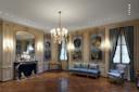 Elegant, ornate room with wood floors, a grand chandelier, gilded mirror, marble fireplace, classical sculptures, blue upholstered sofa and chair, tall windows with blue drapes, and elaborate wall paintings.