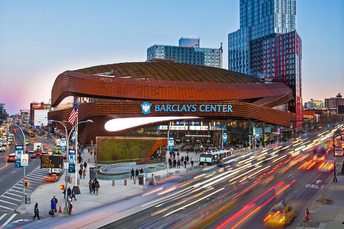 Exterior of Barclays Center at dusk with cars passing by