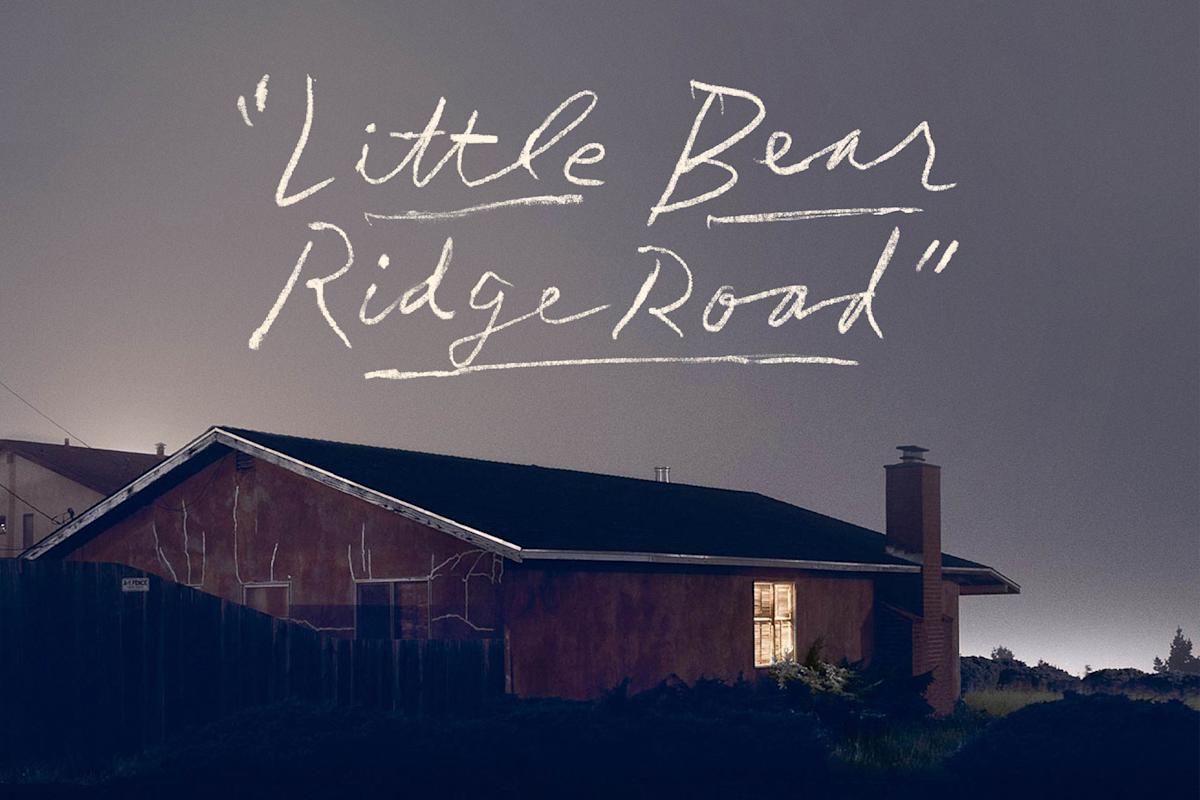 A house with a dark roof and a single lit window is seen at dusk, with the handwritten words "Little Bear Ridge Road" in white above it against a gray-blue sky.