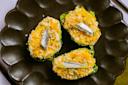 Three halved romaine lettuce boats on a dark scalloped plate, topped with crumbled cheese, breadcrumbs, herbs, and small fish fillets.