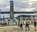 A group of people running in front of the Brooklyn Bridge 