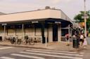 A street corner with the restaurant Soleluna, featuring outdoor seating, bicycles parked nearby, and a group of people standing on the sidewalk near a one-way street sign.