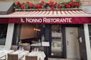 Street view of Il Nonno Ristorante with a red and white striped awning, floral decorations above, and outdoor tables set with white tablecloths, wine glasses, and wicker chairs. The address "2517" is on the door.