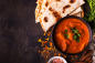 a bowl of red curry next to some pita bread.